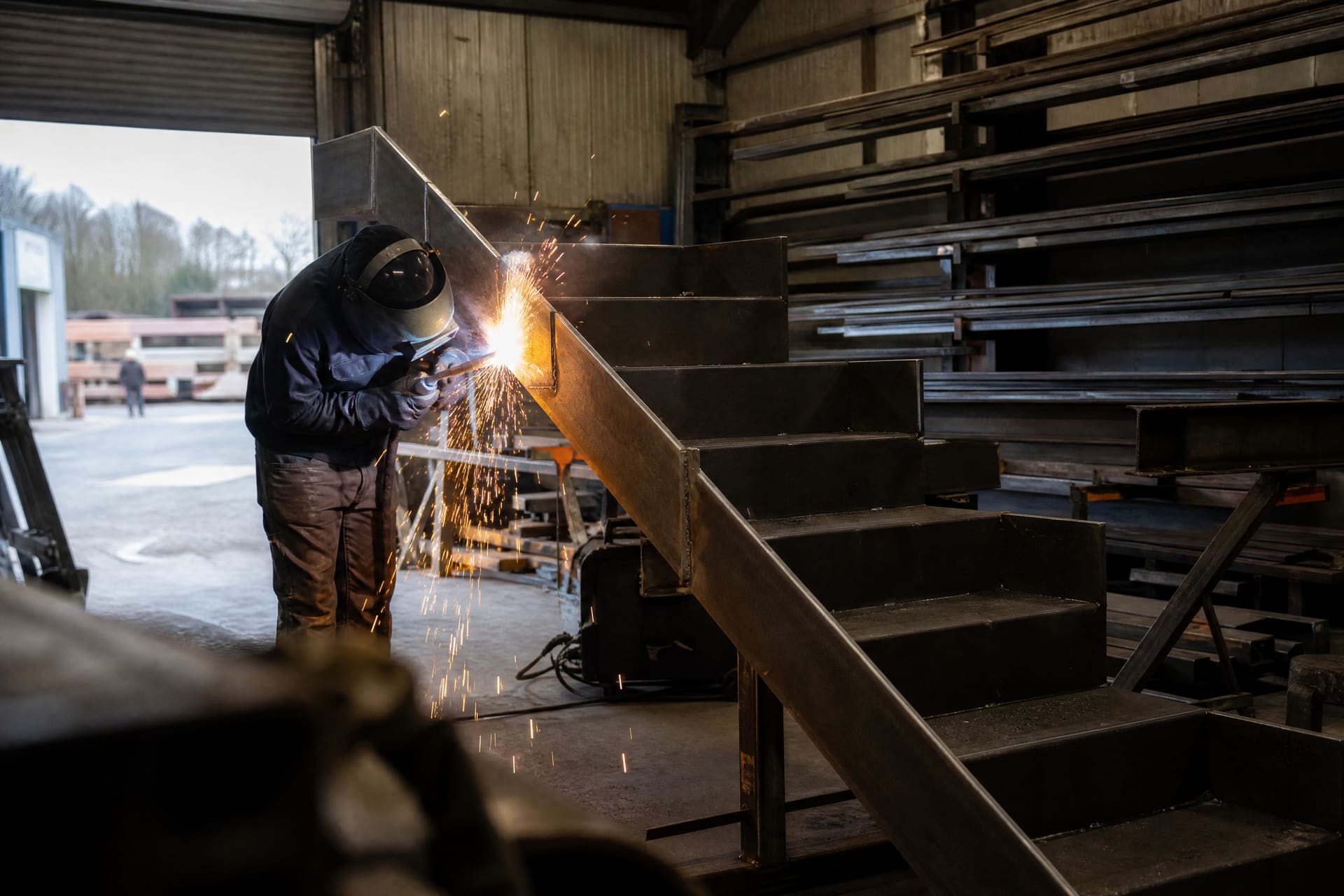 A fabricator welding a steel staircase in the Ironvale workshop